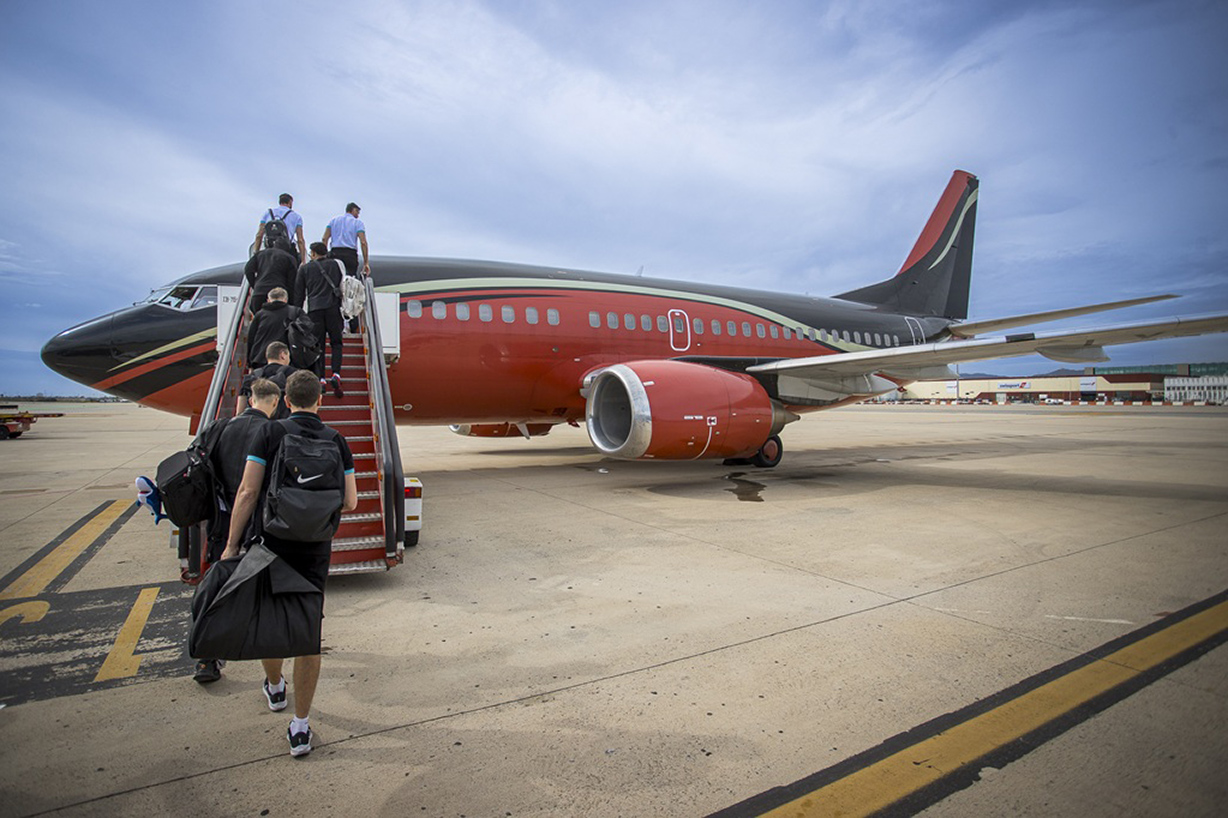 Sportteam steigt in rot-schwarzes KlasJet-Charterflugzeug auf dem Rollfeld